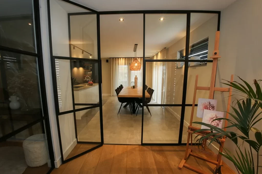 Moderne uitbouw met glazen wanden en houten staanders bij woning aan de Schouw